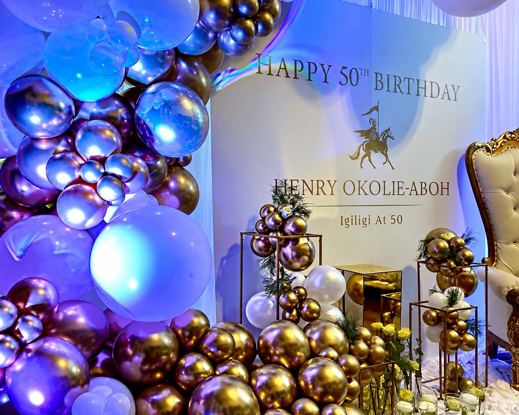 Fiftieth birthday installation: gold and chrome balloon garland, a lettered backdrop and a gilded throne