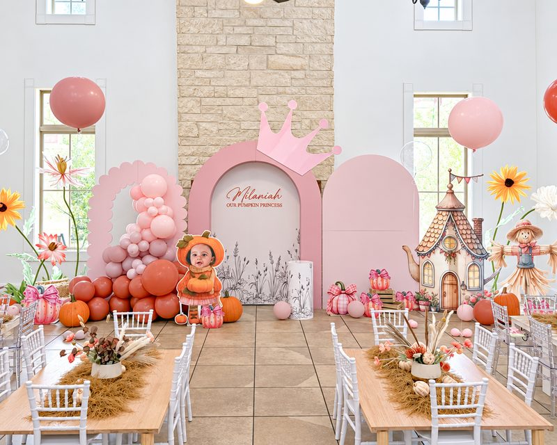Pink pumpkin-themed children's party with an arched backdrop, pumpkins and a long kids' table